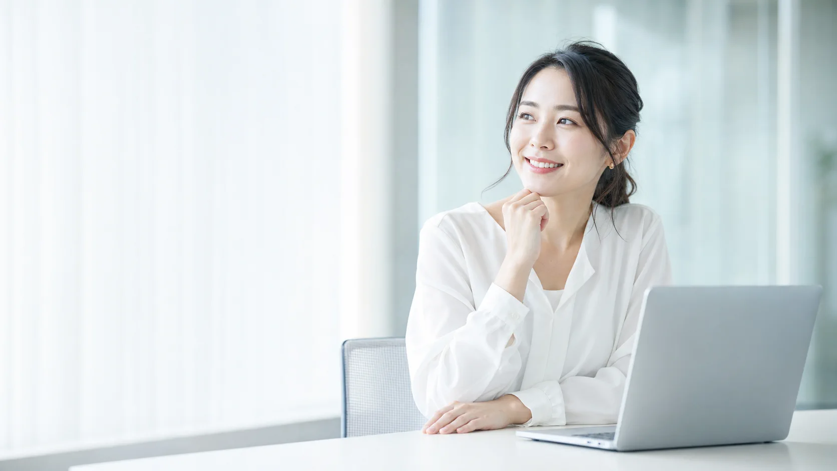 明るいオフィスでノートパソコンを前に生成AIの学び方を考える女性